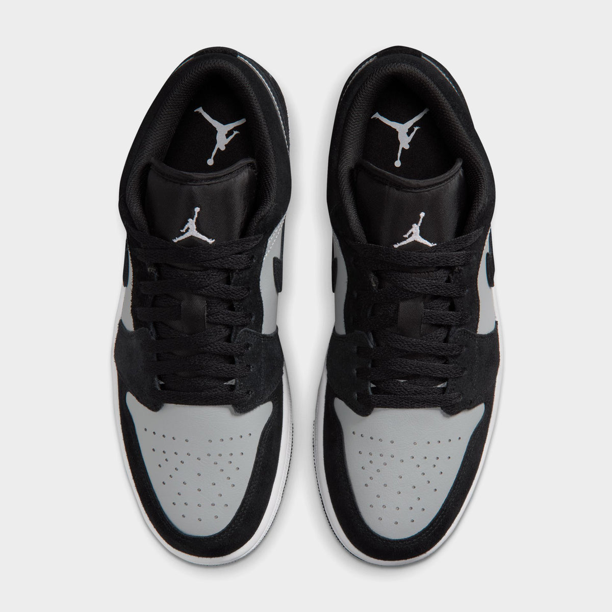 Jordan 1 Low. Top view of black, white and light smoke grey sneakers showing black laces, white toe boxes and padded collars.