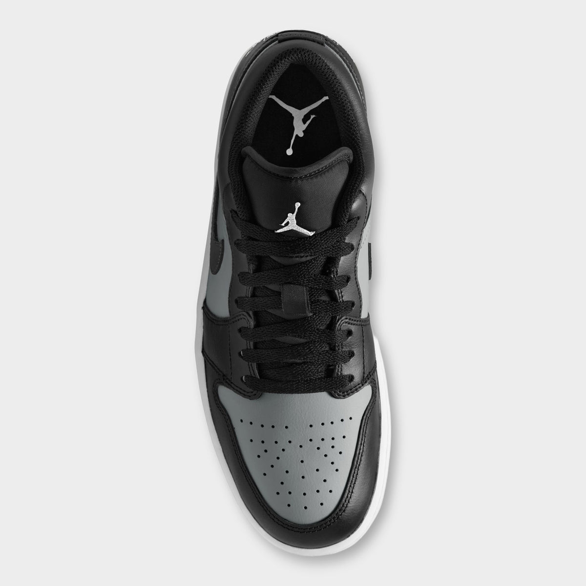 Jordan 1 Low. Top view of black, white and light smoke grey sneaker showing black laces, padded tongue and perforated white toe box.