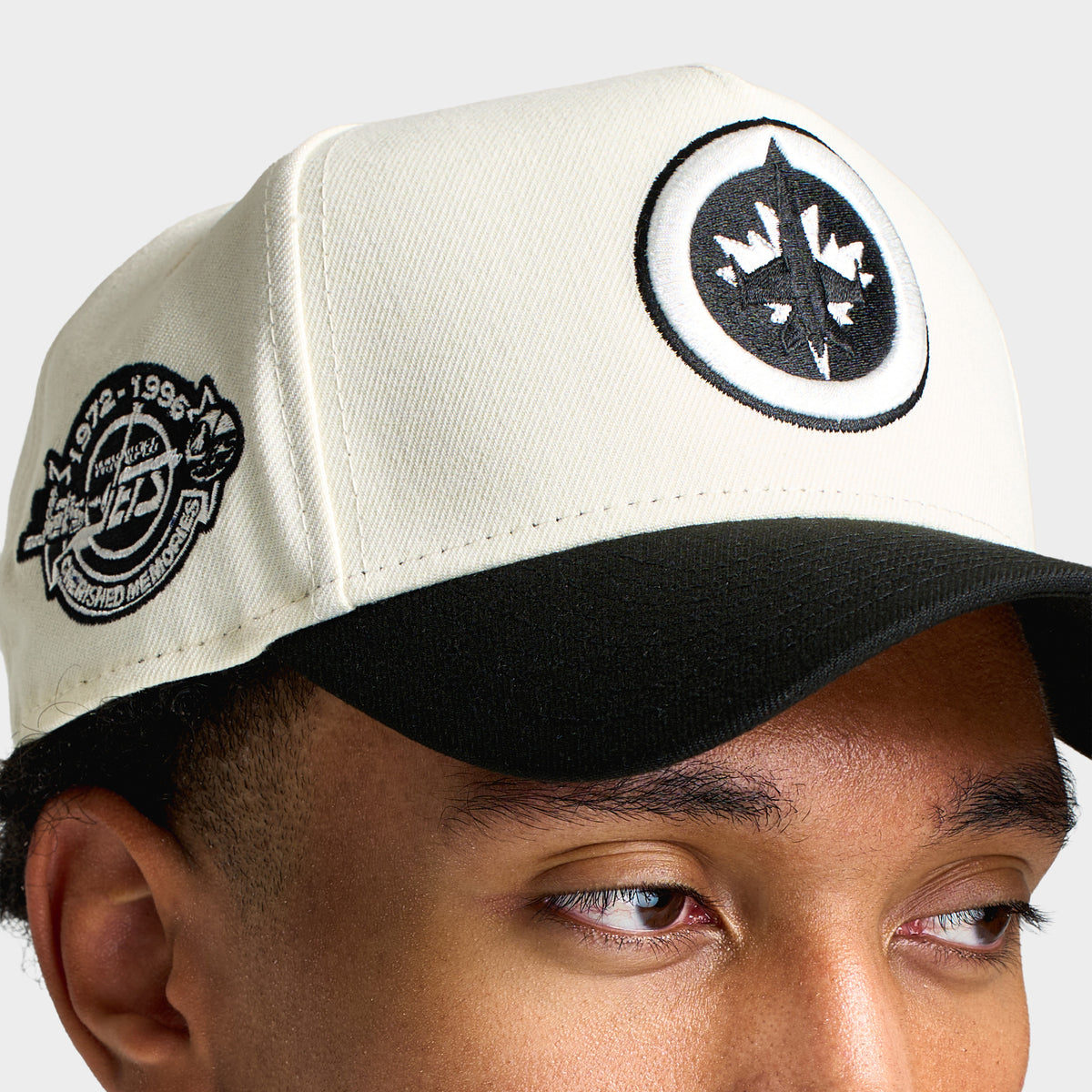 New Era Winnipeg Jets 9FORTY A-Frame. Close-up view highlighting round black Winnipeg Jets crest patch, chrome crown, commemorative side patch, and black visor.