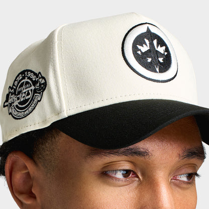 New Era Winnipeg Jets 9FORTY A-Frame. Close-up view highlighting round black Winnipeg Jets crest patch, chrome crown, commemorative side patch, and black visor.