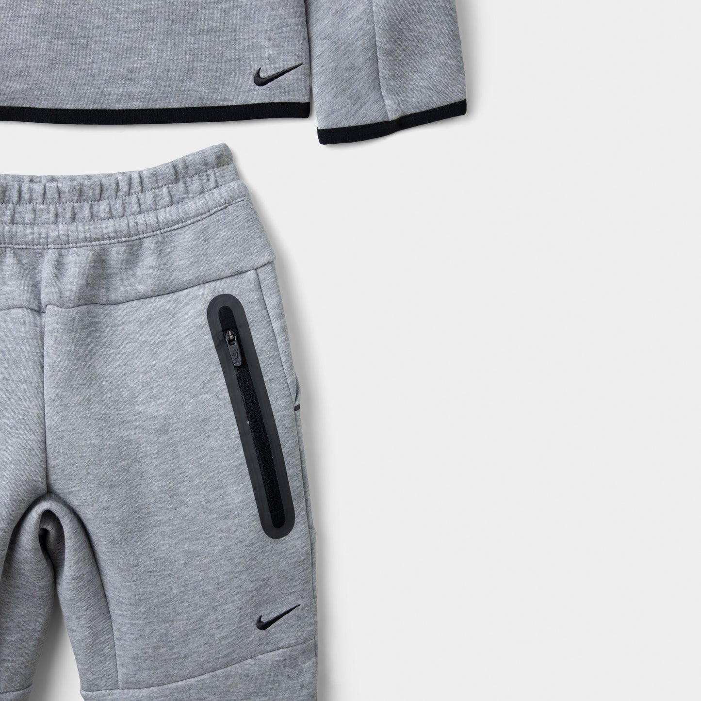 Nike Sportswear Children's Tech Fleece Full Zip Hoodie Set. Close-up of dark grey heather joggers showing the elastic waistband, zip pocket and black trim.