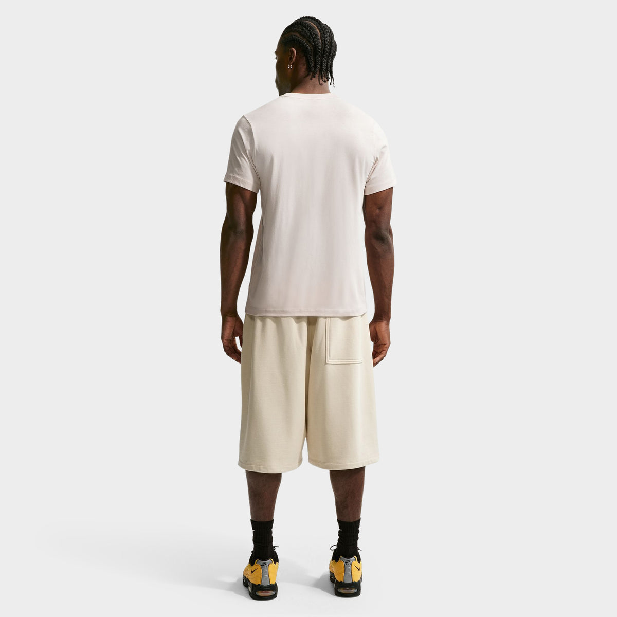 Nike Sportswear Club Tee. Full-body back view of model wearing light orewood brown T-shirt with matching shorts and dark shoes.