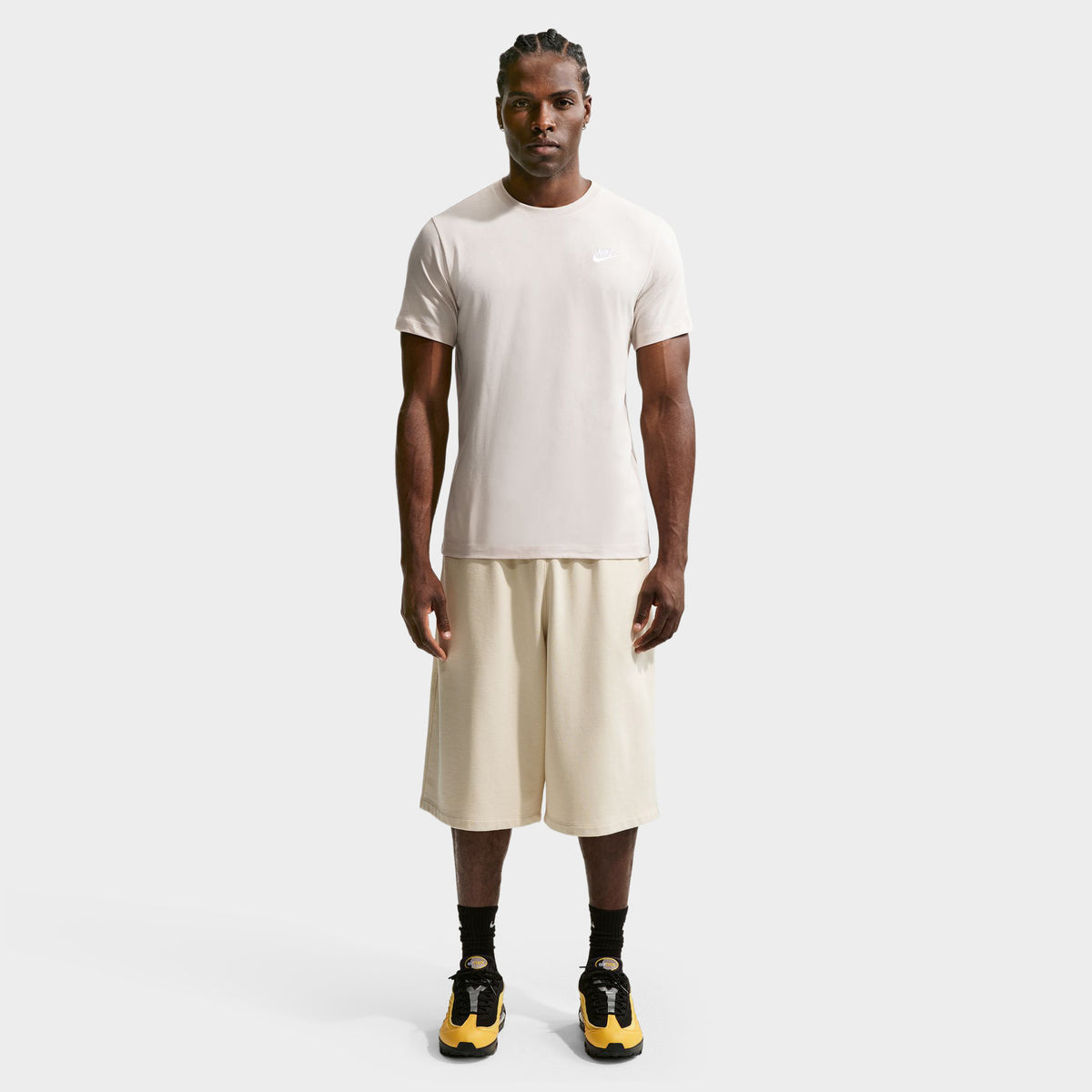Nike Sportswear Club Tee. Full-body front view of model wearing light orewood brown T-shirt with matching shorts and dark shoes.