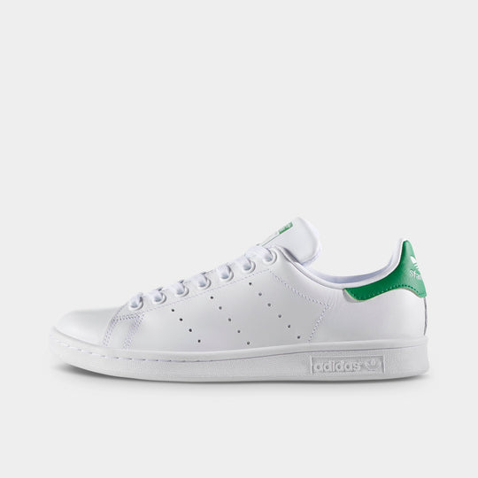 adidas Women's Stan Smith. Side view of white and green sneaker with perforated three stripes, green heel tab and white sole.