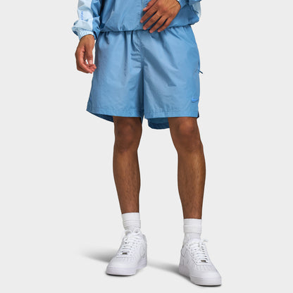 Nike NOCTA Cardinal Nylon Shorts. Front lower body model view of work blue nylon shorts featuring an elasticated waistband, side slip pockets, tonal stitching, relaxed fit, and vented side hems. 