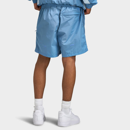 Nike NOCTA Cardinal Nylon Shorts. Rear lower body model view showing the back of the work blue nylon shorts, rear zip welt pocket, and straight open hems.