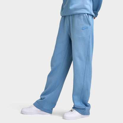 Nike NOCTA Fleece Open Hem Pants. Side view of model wearing work blue sweatpants with relaxed legs and open hems.