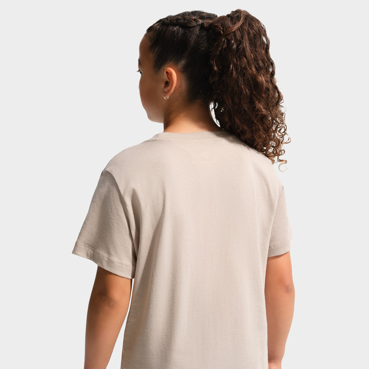 Nike Juniors' Futura T-Shirt. Upper body rear view showing a youth model in the moon particle beige shortsleeve t-shirt, highlighting the smooth back fabric and shoulder seams.
