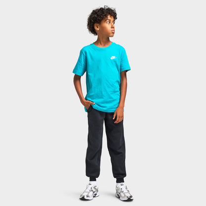Nike Juniors' Futura T-Shirt. Full-length front model view styled with dark grey joggers and white athletic sneakers. 