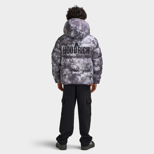 Hoodrich Juniors' Ark Puffer Jacket. Full-length back view of model wearing digital camo puffer jacket with bold rear branding, styled with black pants. 