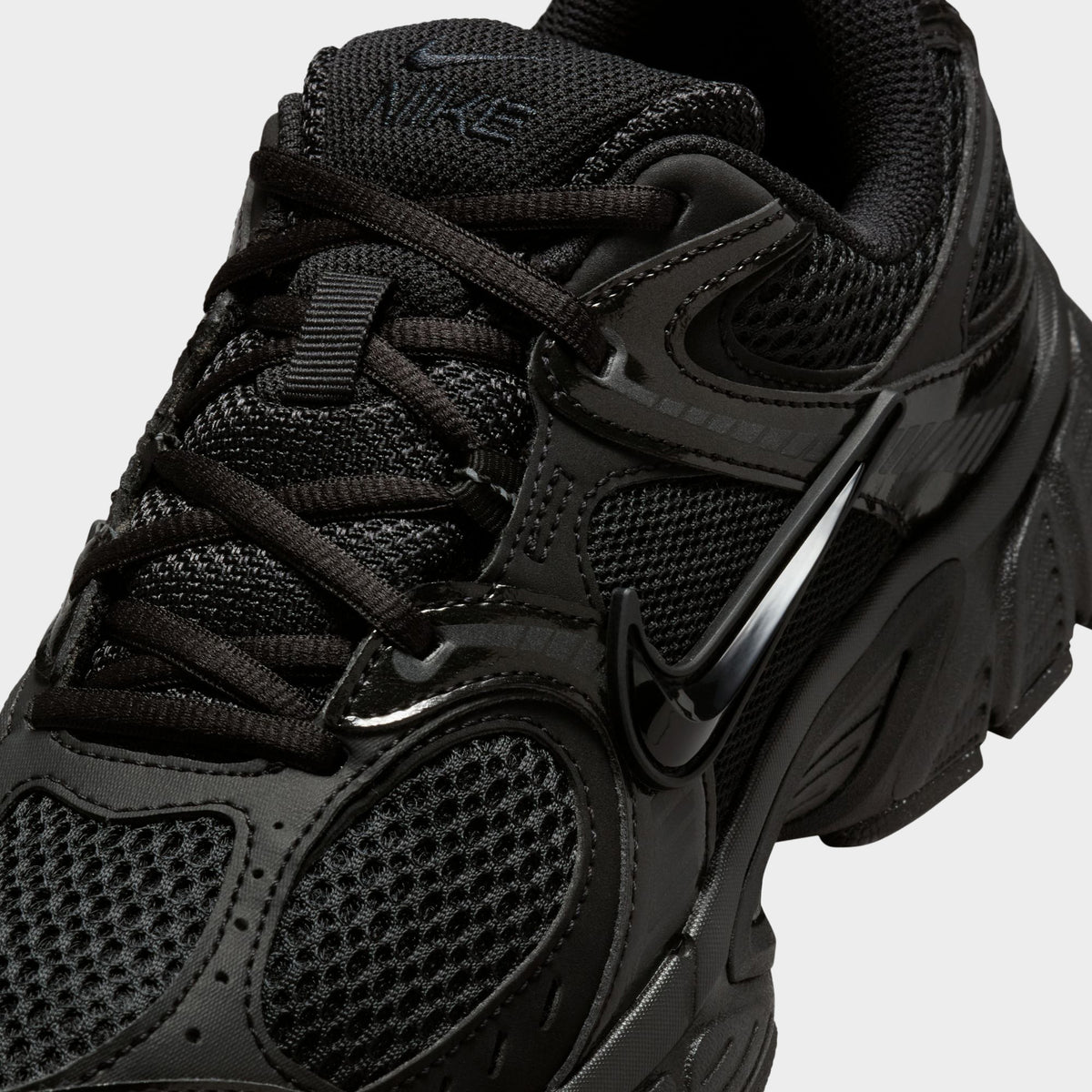 Nike Women's V5 RNR. Close-up of black and anthracite sneaker showing black laces, mesh toe box and glossy overlays.
