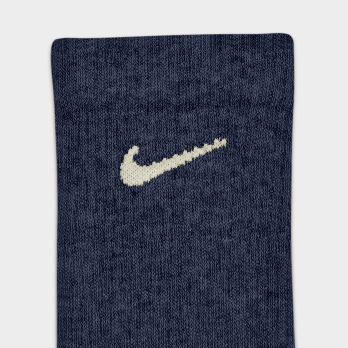 Nike Everyday Elevated Crew Socks (6-Pack). Close-up of navy crew sock showing ribbed knit texture and cream Nike Swoosh logo.