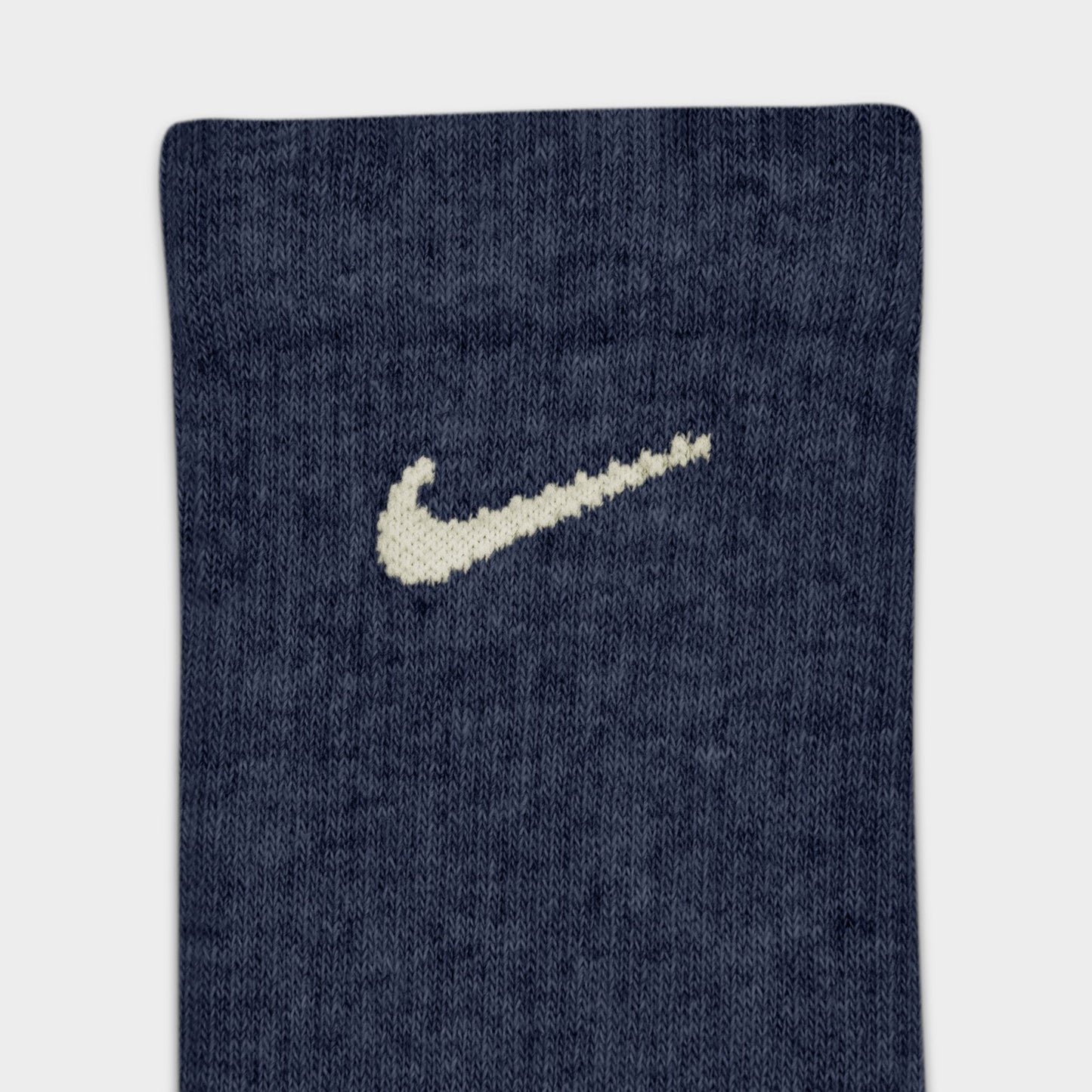 Nike Everyday Elevated Crew Socks (6-Pack). Close-up of navy crew sock showing ribbed knit texture and cream Nike Swoosh logo.
