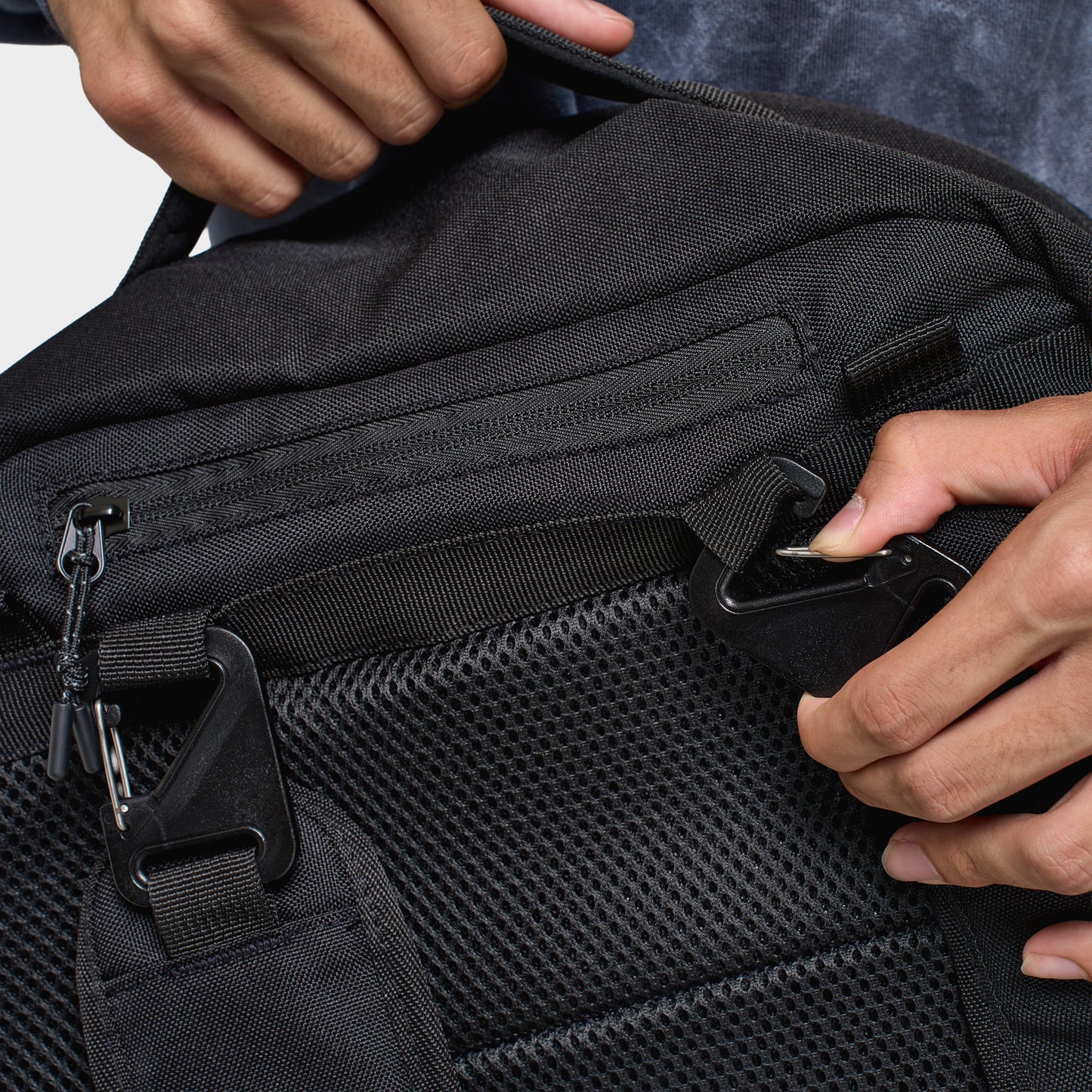 Hoodrich Varso Backpack. Close-up of black backpack showing zippered front compartments, mesh pocket and textured fabric panels.