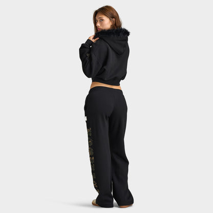 Hoodrich Women's Camo Rift Boxy Zip-Through Hoodie. Full-length three-quarter back view showing the cropped silhouette of the black hoodie paired with matching black sweatpants. 