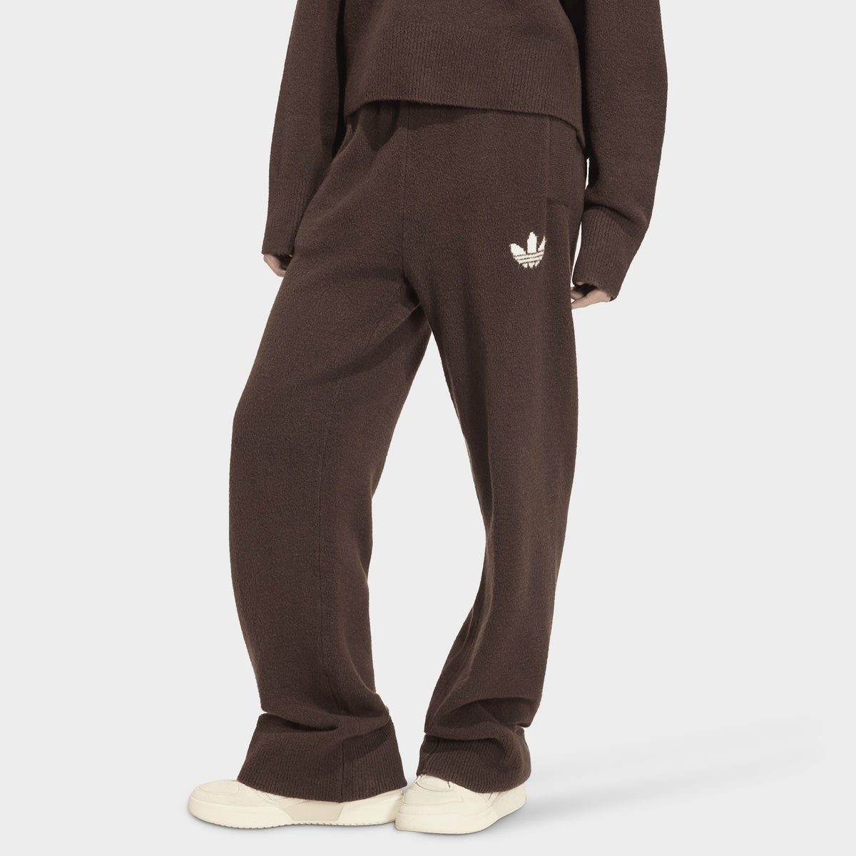adidas Essentials Knit Pant. Front view of model wearing aurora coffee pants with wide legs, elastic waistband and white Trefoil logo.