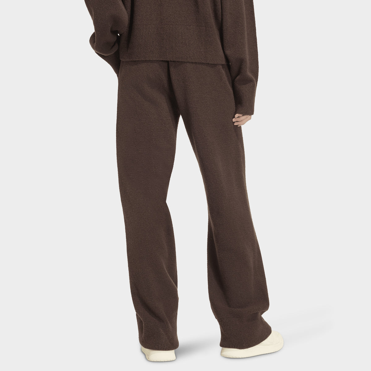 adidas Essentials Knit Pant. Back view of model wearing aurora coffee pants with wide legs and elastic waistband.