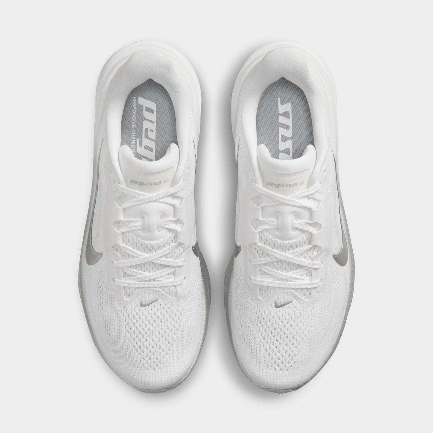 Nike Women's Pegasus 42. Top view of white, metallic silver and wolf grey running shoes showing white laces, padded tongues and mesh toe boxes.
