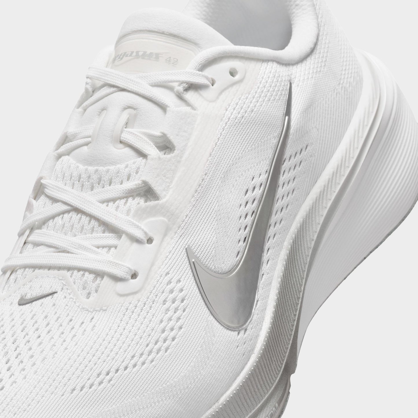 Nike Women's Pegasus 42. Close-up of white, metallic silver and wolf grey running shoe showing white laces, mesh panels and silver Swoosh.