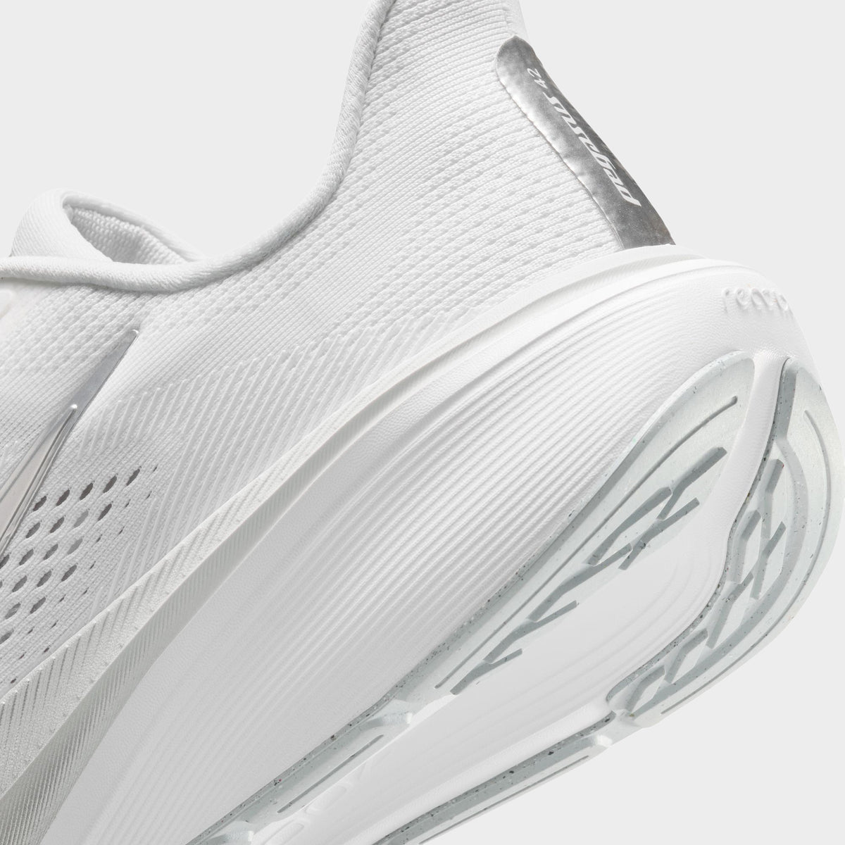 Nike Women's Pegasus 42. Close-up of white, metallic silver and wolf grey running shoe showing padded heel, reflective strip and layered midsole.