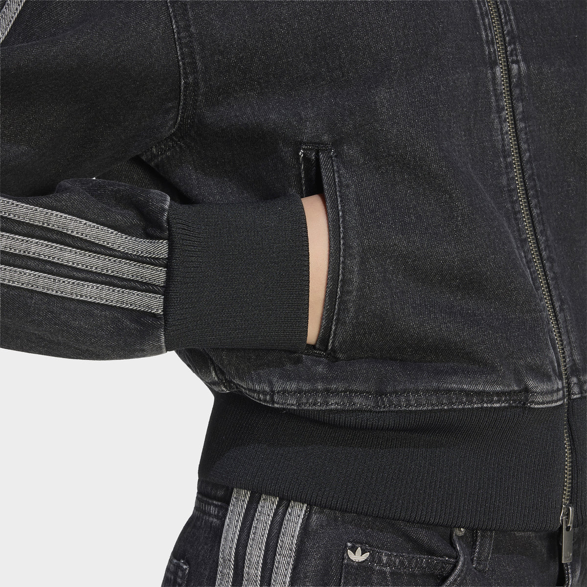 adidas Firebird Denim Track Top. Close-up of true black denim track jacket showing zippered side pocket, contrast stitching and striped sleeve.
