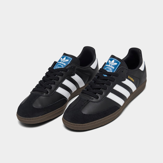 adidas Originals Women's Samba OG. Three-quarter view of core black, white and clear granite sneakers with black laces, white three stripes and dark gum soles.