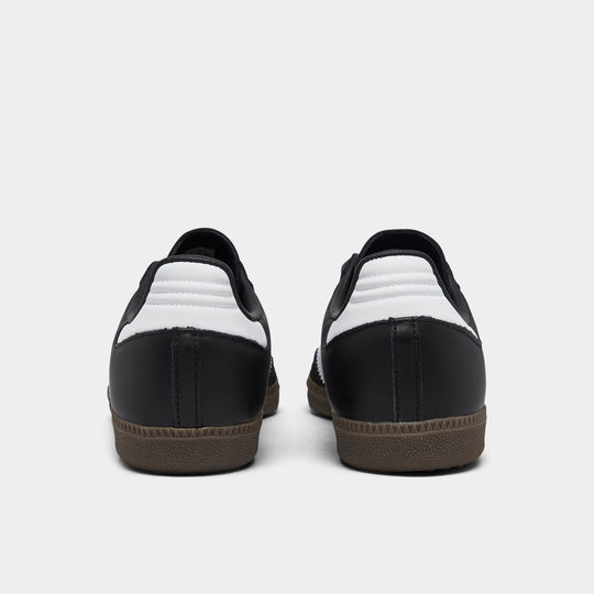 adidas Originals Women's Samba OG. Rear view of core black, white and clear granite sneakers with white heel tabs, black uppers and dark gum soles.