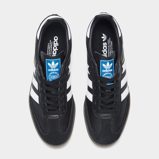 adidas Originals Women's Samba OG. Top view of core black, white and clear granite sneakers showing black laces, blue tongue labels and white heel details.