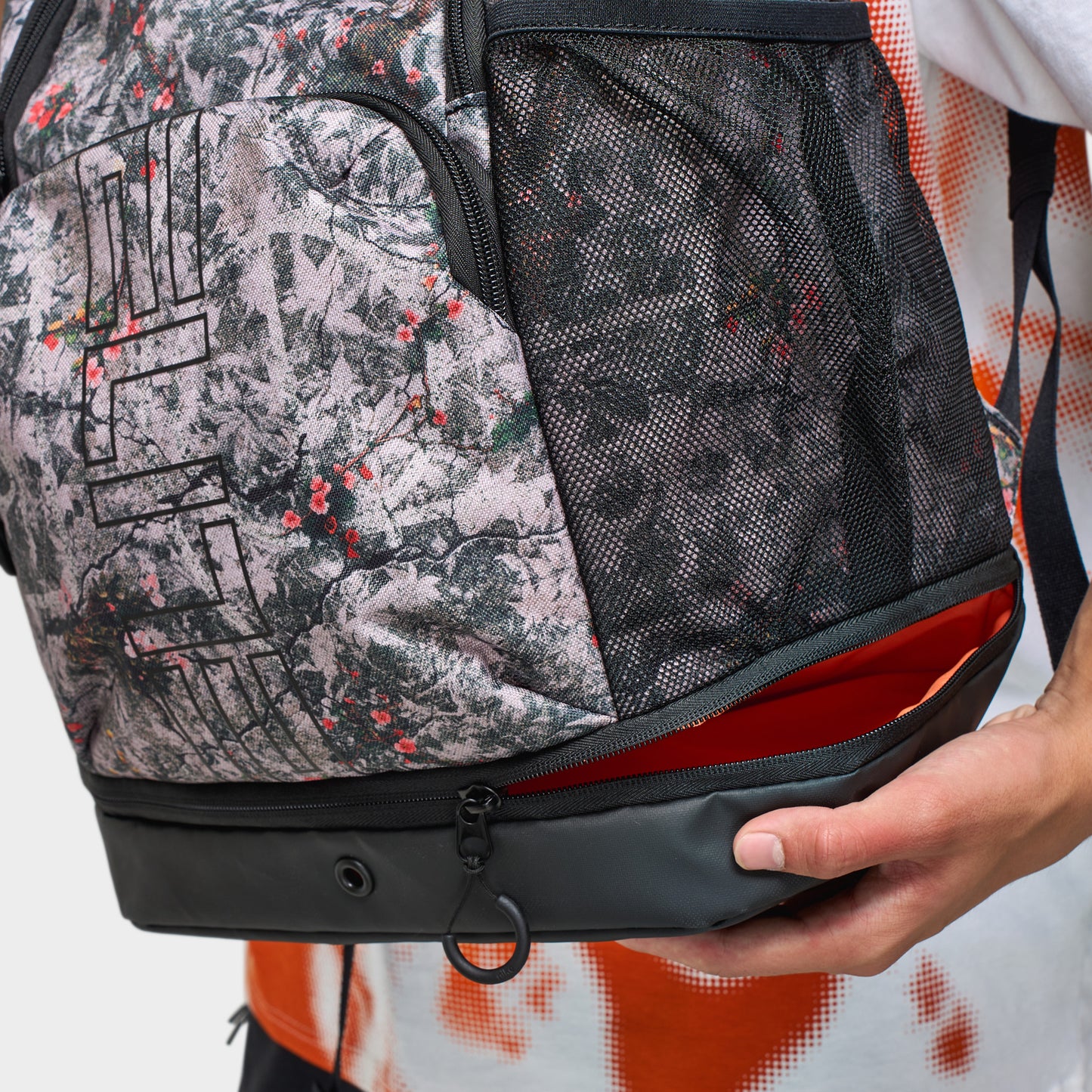 Nike Varsity Elite Backpack. Close-up of cream and black backpack showing patterned front pocket, black base panel and zippered compartment.