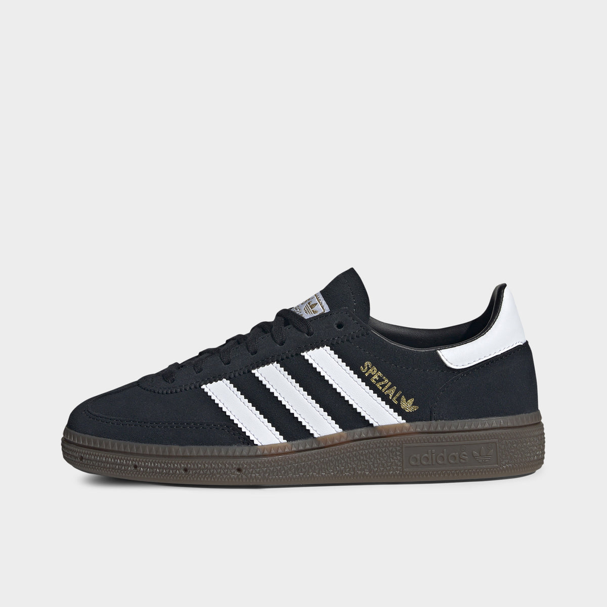 adidas Juniors' Handball Spezial. Side view of black, white and gum junior sneaker with white three stripes, gold Spezial branding and gum sole.