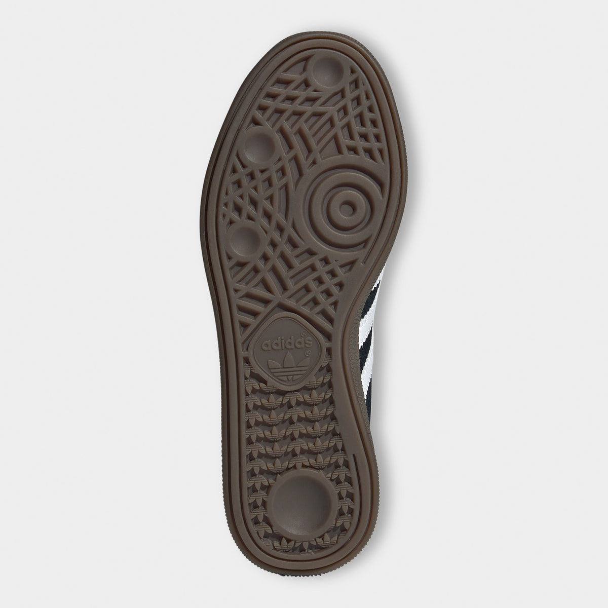 adidas Juniors' Handball Spezial. Bottom view of black, white and gum junior sneaker showing brown gum outsole with circular forefoot tread.