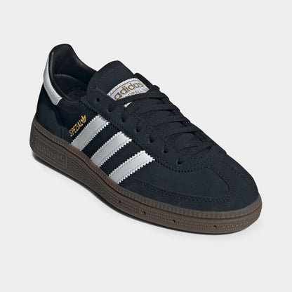 adidas Juniors' Handball Spezial. Three-quarter view of black, white and gum junior sneakers with black laces, white three stripes and gum soles.