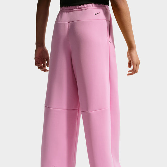 Nike Juniors’ Sportswear Tech Fleece Wide Leg Pant. Rear lower body model view showing the back of the pink rise Tech Fleece pants, elastic waistband, horizontal darting across the knee, and wide open-leg hems. 