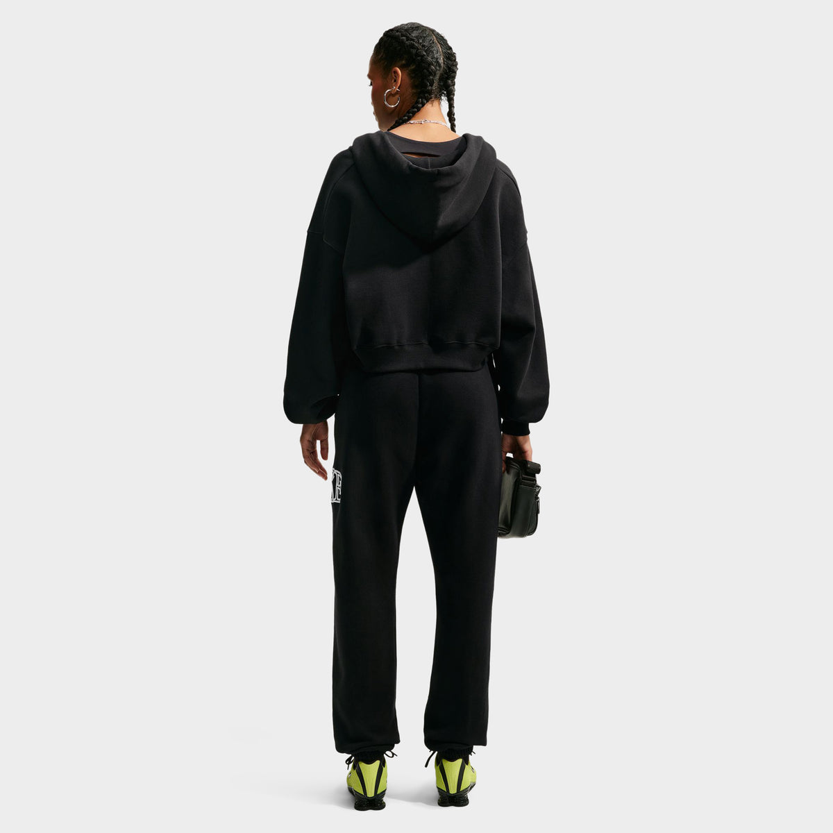 Nike Studio Fleece Cropped Full Zip Hoodie. Full-body back view of model wearing black cropped hoodie with matching black pants.