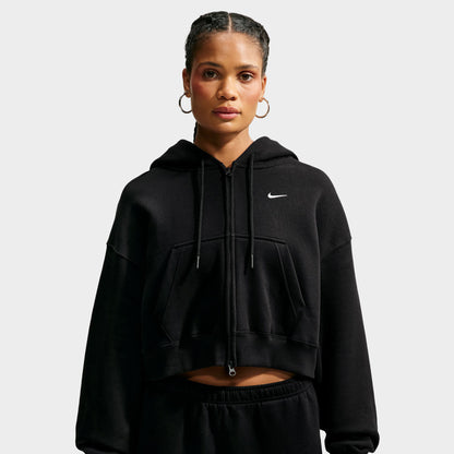 Nike Studio Fleece Cropped Full Zip Hoodie. Front view of model wearing black cropped hoodie with full-zip closure, drawstring hood and small white Nike Swoosh.