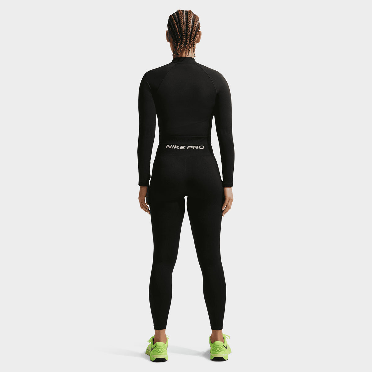 Nike Pro Women's Dry Fit Seamless Fullzip. Back view of model wearing black full-zip top with fitted shape and long sleeves.