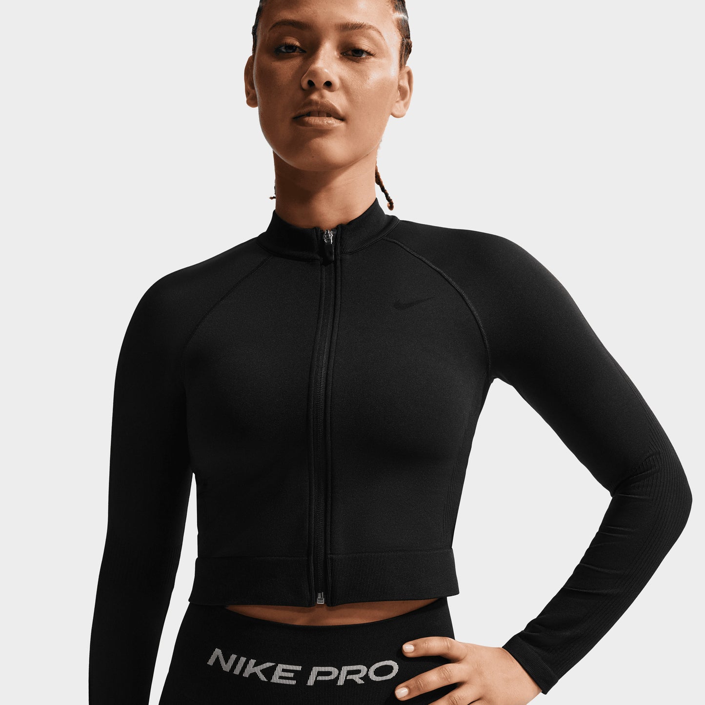 Nike Pro Women's Dry Fit Seamless Fullzip. Three-quarter view of model wearing black full-zip top with high collar and fitted sleeves.