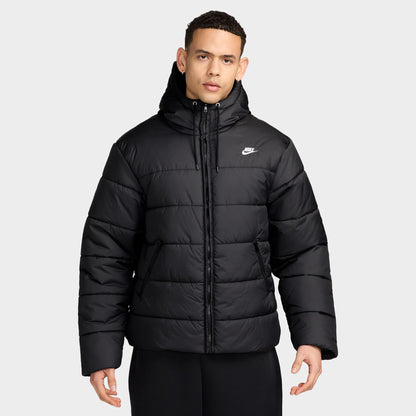 Nike Access Filled Puffer. Front view of model wearing black puffer jacket with hood, zip closure, quilted panels and white Nike Swoosh.