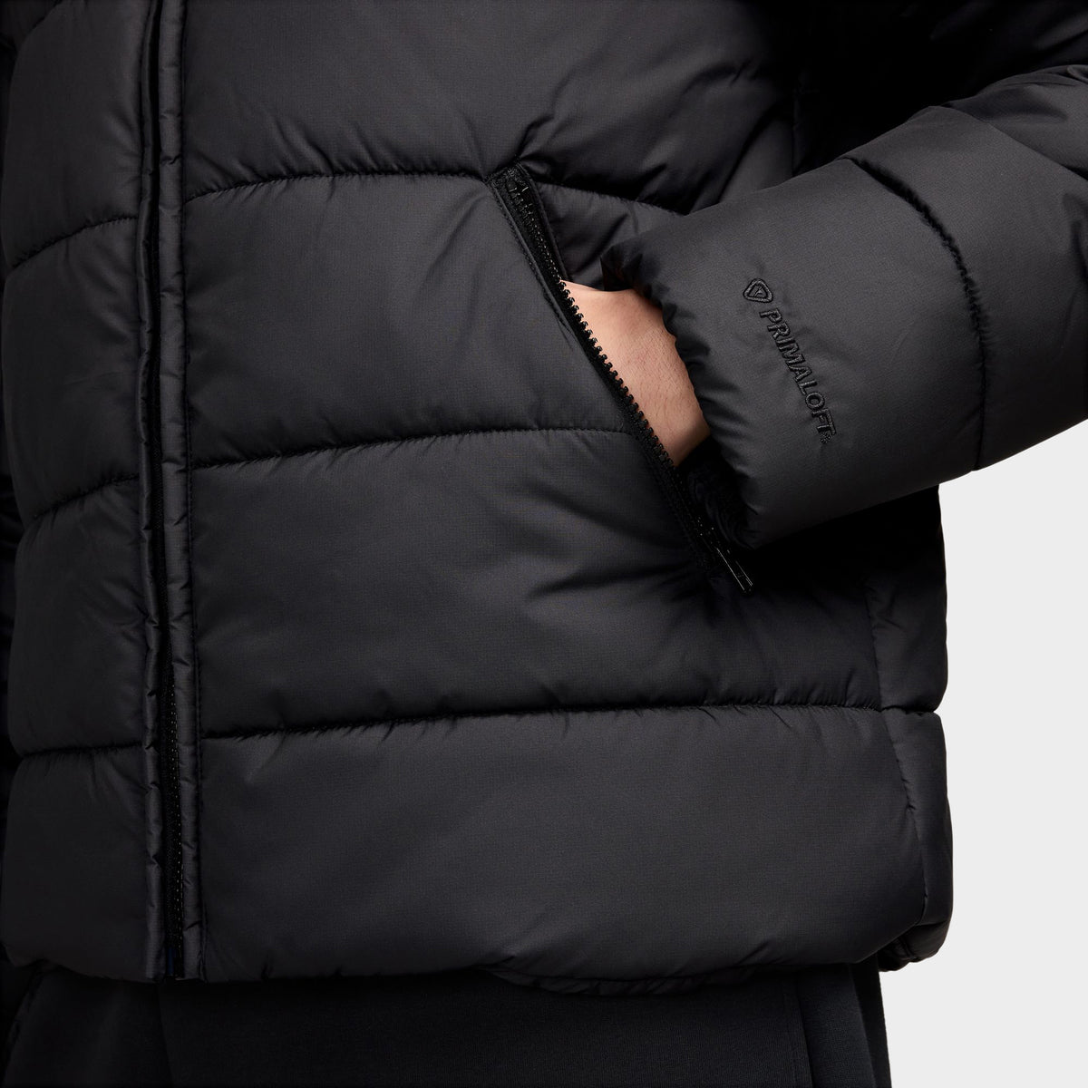 Nike Access Filled Puffer. Close-up of black puffer jacket showing side pocket, quilted panels and elastic cuff.
