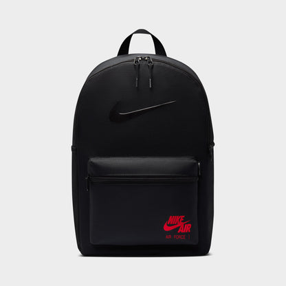 Nike AF1 Heritage Backpack. Front view of black backpack with zippered main compartment, front pocket and red Nike Air Force 1 branding.