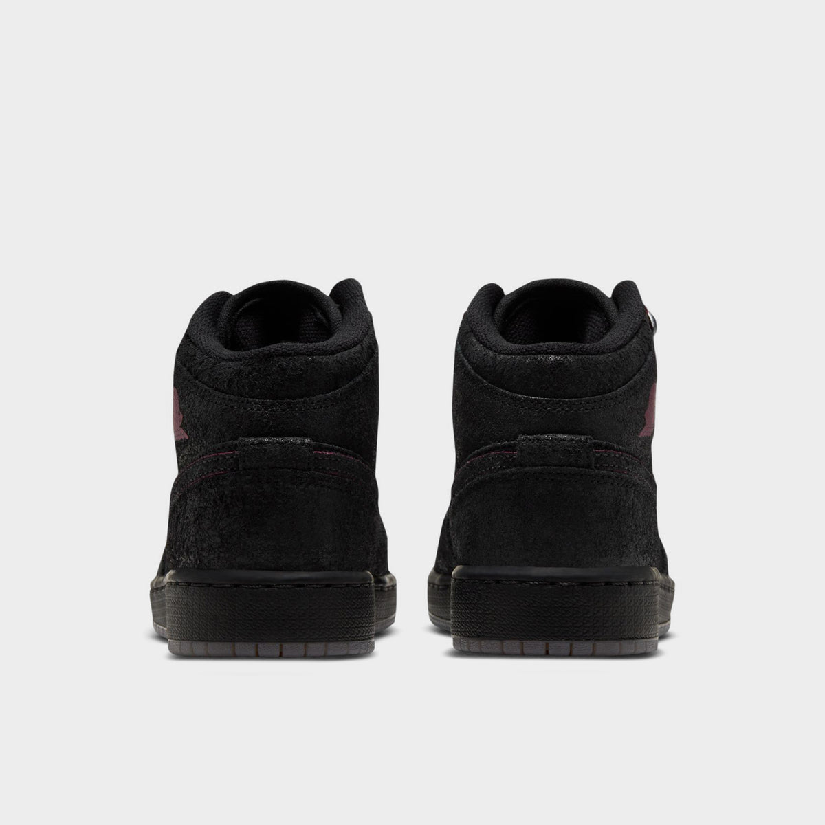 Jordan 1 Mid SE GS. Rear view displaying black textured leather heel overlays, padded ankle collar, and solid black midsoles. 