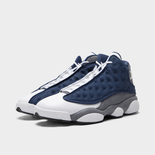 Jordan 13 Retro. Three-quarter view of navy and university blue basketball sneakers with white laces, dimpled uppers and sculpted soles.