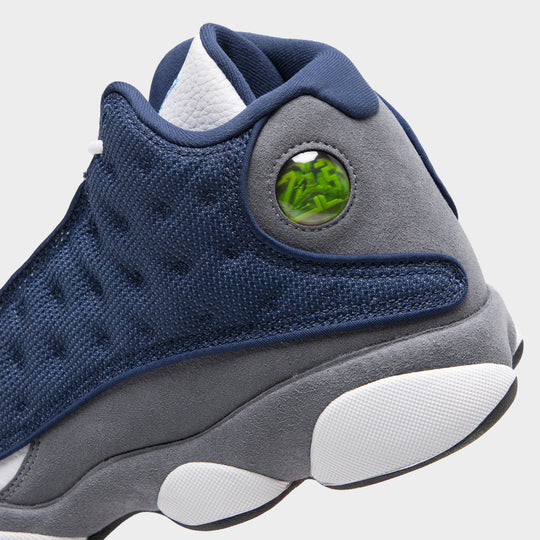Jordan 13 Retro. Close-up of navy and university blue basketball sneaker showing dimpled panels, green hologram detail and sculpted grey midsole.