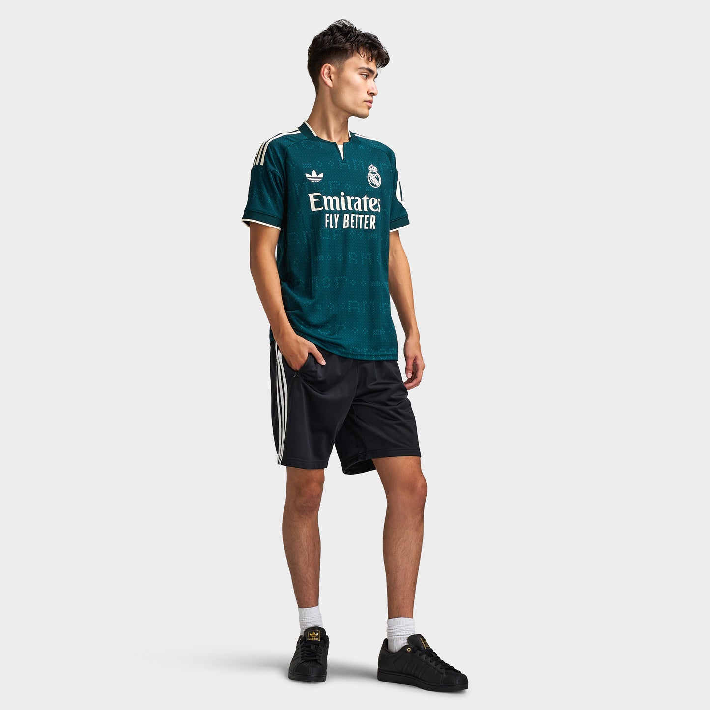 adidas Real Madrid Away Jersey. Full-body front view of model wearing aurora ivy soccer jersey with black shorts and dark shoes.