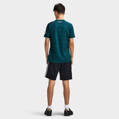 adidas Real Madrid Away Jersey. Full-body back view of model wearing aurora ivy soccer jersey with black shorts and dark shoes.