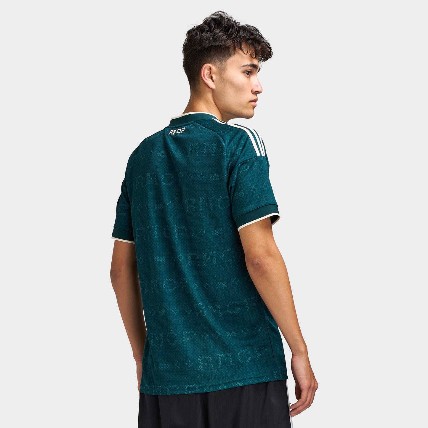 adidas Real Madrid Away Jersey. Back three-quarter view of model wearing aurora ivy soccer jersey with short sleeves and white shoulder stripes.