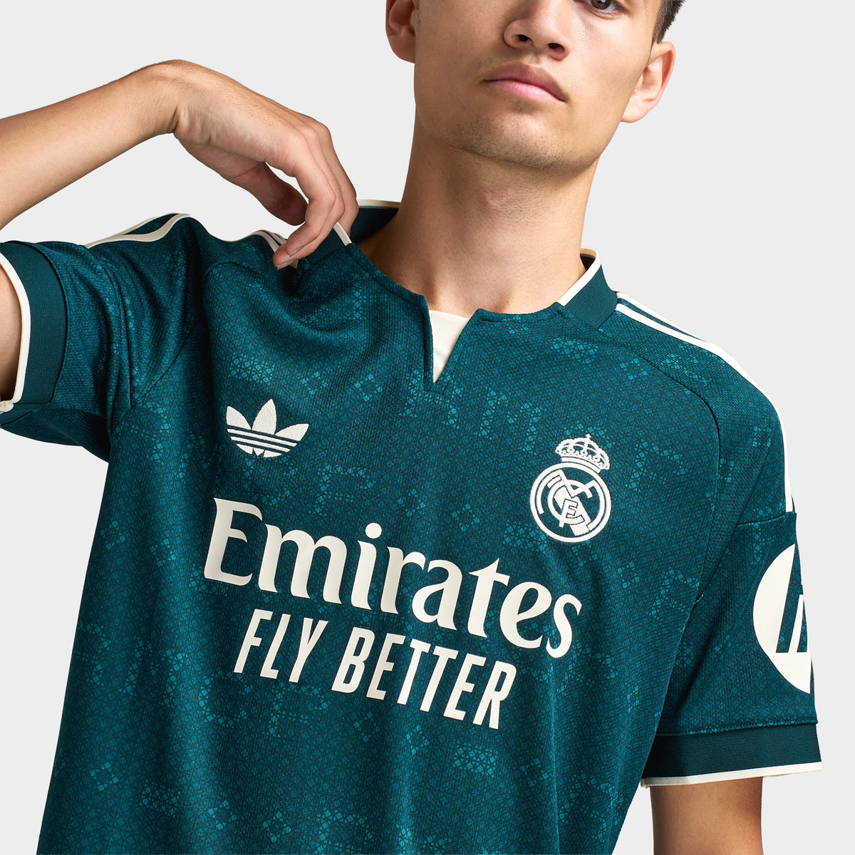 adidas Real Madrid Away Jersey. Close-up of aurora ivy soccer jersey showing the collar, adidas logo, Real Madrid crest and Emirates Fly Better sponsor graphic.