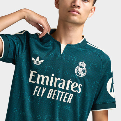 adidas Real Madrid Away Jersey. Close-up of aurora ivy soccer jersey showing the collar, adidas logo, Real Madrid crest and Emirates Fly Better sponsor graphic.
