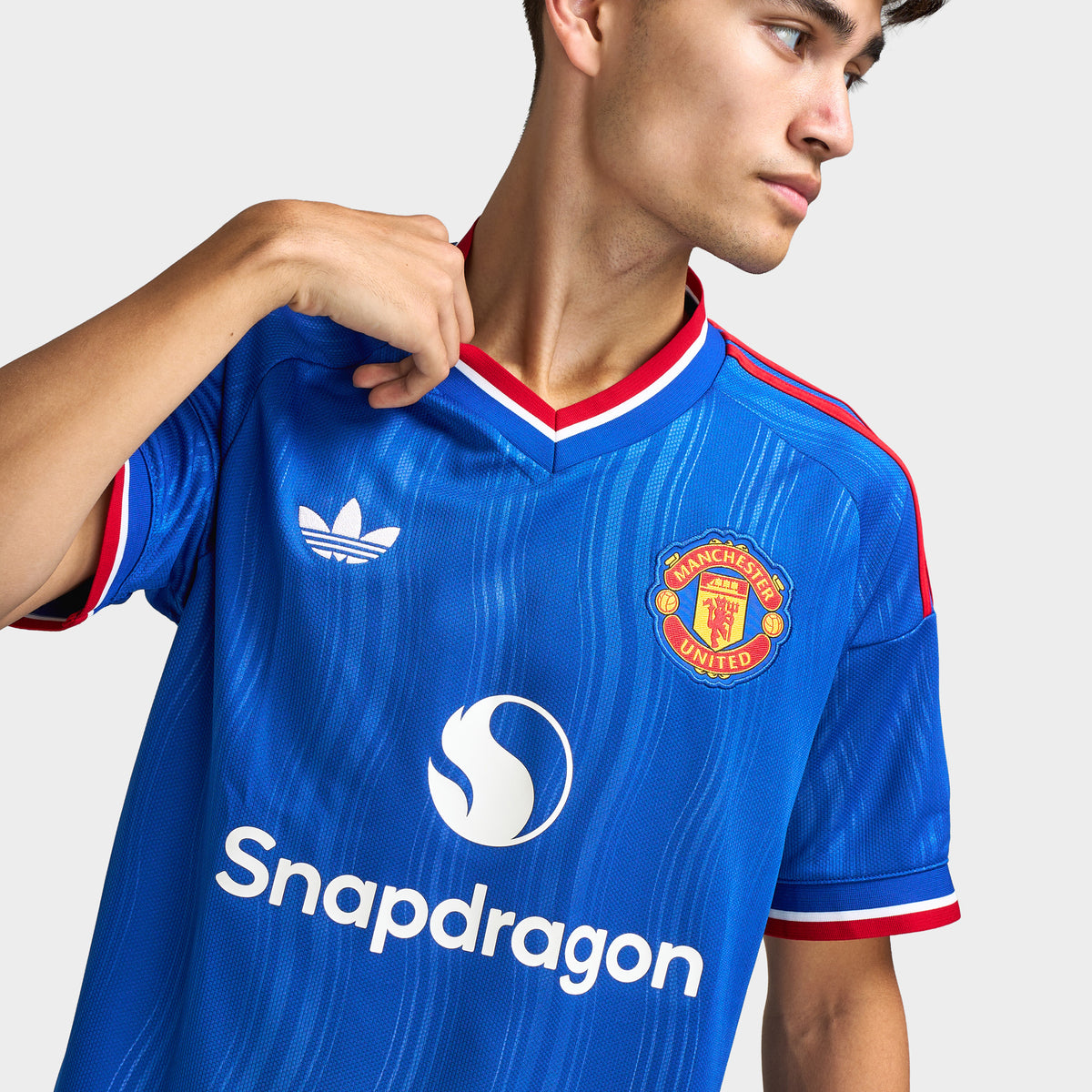 adidas Manchester United Away Jersey. Close-up of team royal blue soccer jersey showing red-trimmed collar, adidas logo, Manchester United crest and Snapdragon sponsor graphic.