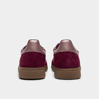 adidas Women's Handball Spezial. Rear view of a pair of low-top sneakers displaying maroon suede heel counters, metallic vapour grey leather heel tabs, and low-profile gum rubber soles. 